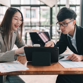 Two government workers inspecting a tablet with IBISWorld data